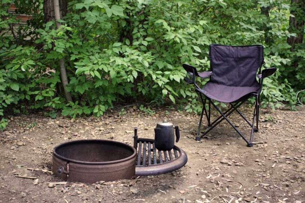 Una silla de camping plegable frente a una hoguera.